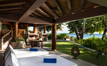 One-bedroom villa pavilion at Amanpulo with covered seating area, plunge pool, and views across manicured gardens to the Palawan coastline.