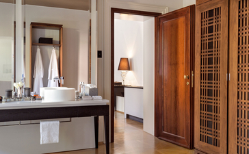 Palazzo Bedroom at Aman Venice hotel, featuring a vanity with mirror, wooden wardrobe and neutral décor.