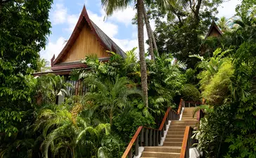 Pavilion with golden roof nestled amongst tropical foliage at Amanpuri resort, Thailand.