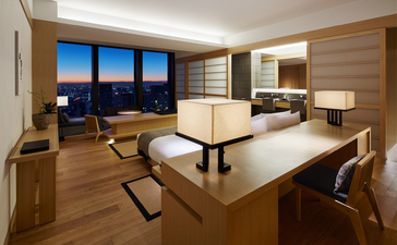Premier Room at Aman Tokyo with dining table, seating area, and Tokyo skyline views through floor-to-ceiling windows.