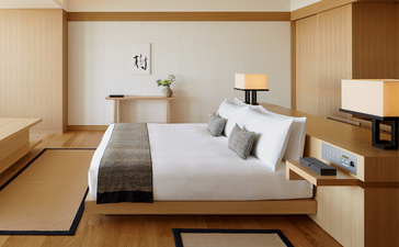 Principal bedroom in a Premier Room at Aman Tokyo, featuring a platform bed with neutral bedding and wooden architectural details.