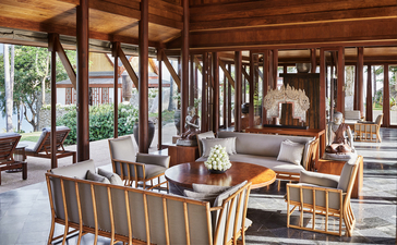 Airy dining pavilion at Amanpuri resort with wooden beams, natural light, and ocean views.