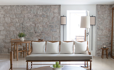 St. Sava Cottage living room at Aman Sveti Stefan, with neutral seating and stone walls.