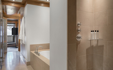 Principal bedroom ensuite at Aman Le Mélézin with neutral tones and wooden beams.