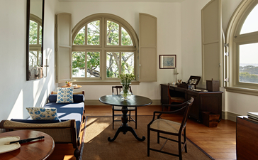 Suite sitting room at Amangalla with arched windows, wooden furniture, and colonial architecture in Sri Lanka.