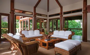 Chambre spacieuse aux trois lits à Amanpulo, resort des Philippines, avec baies vitrées donnant sur la végétation tropicale.