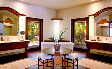 安缦璞乐度假村的三卧室别墅浴室，配有对称的双盥洗台、拱形镜子和紫色墙壁。