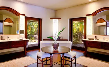 Spacious principal bedroom with dual vanities and arched mirrors at Amanpulo resort, Palawan.