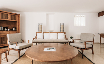 Three-bedroom village cottage living room at Aman Sveti Stefan, Montenegro, with round wooden table and neutral furnishings.