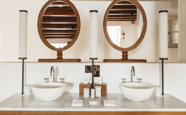 Three-bedroom cottage bathroom at Aman Sveti Stefan with dual circular mirrors and marble vanity, Montenegro.