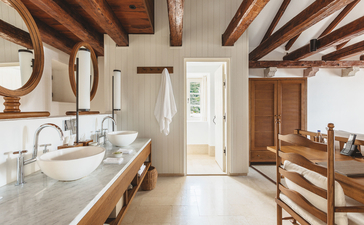 Three-bedroom village cottage bathroom at Aman Sveti Stefan, Montenegro, with wooden beams and stone finishes.