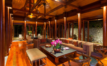 Dining hall with wooden beams and floor-to-ceiling windows at Amanpuri resort, Thailand.