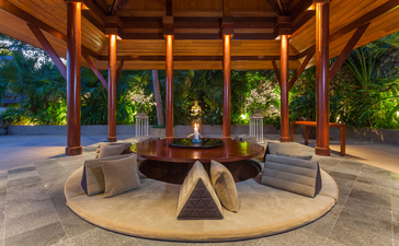 Überdachter Pavillon mit Sitzbereichen und Feuerstelle im Amanpuri Resort, Thailand.