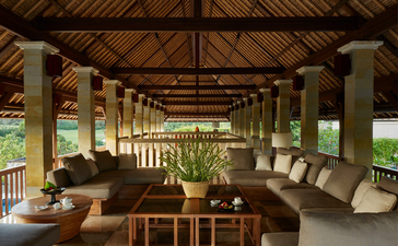 Three-bedroom villa lounge with timber ceiling, stone columns and garden views at Aman Villas at Nusa Dua.