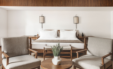 Two-bedroom suite at Aman Sveti Stefan with seating area, wooden furniture and Adriatic views.