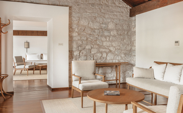 Two-bedroom suite with sitting area, stone fireplace, and coastal views at Aman Sveti Stefan, Montenegro.