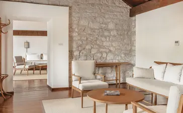 Two-bedroom suite with sitting area, stone fireplace, and coastal views at Aman Sveti Stefan, Montenegro.