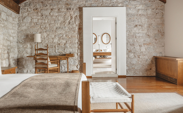 Two-bedroom suite at Aman Sveti Stefan with stone walls, wooden furnishings, and serene coastal aesthetic.