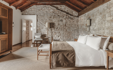 Two-bedroom suite at Aman Sveti Stefan with wooden beams, stone walls and white bedding.
