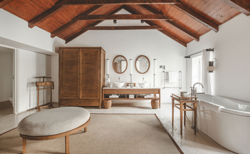 Two-bedroom suite with wooden ceiling beams, neutral furnishings, and Adriatic views at Aman Sveti Stefan, Montenegro.