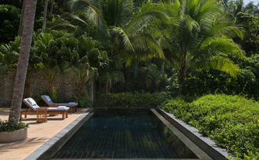 Zwei-Schlafzimmer-Poolpavillon mit langem Swimmingpool, umgeben von tropischer Vegetation bei Amanpuri, Thailand.