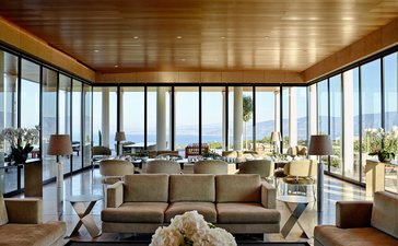 Villa lounge with floor-to-ceiling windows overlooking the Aegean Sea at Amanzoe resort, Greece.