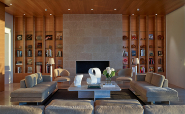 Salon avec foyer central et bibliothèques intégrées à Amanzoe, resort en Grèce.