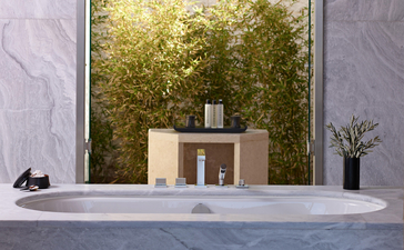 Minimalist bathroom vanity with stone countertop and green foliage beyond, Amanzoe resort, Greece.