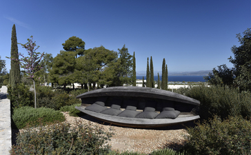 Circular reflecting pool surrounded by cypress trees and Mediterranean landscaping at Amanzoe resort, Greece.