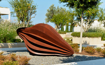 Sculpture de feuille en acier rouille au bord d'un bassin à Amanzoe, resort en Grèce.