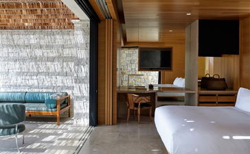 Villa bedroom at Amanzoe resort with sea views and natural light from large windows.