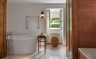 Village Room bathroom at Aman Sveti Stefan, with freestanding bath, wooden accent wall, and coastal views.