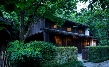 Village Villa at Amanfayun nestled amongst verdant woodland, with timber architecture and lush greenery.