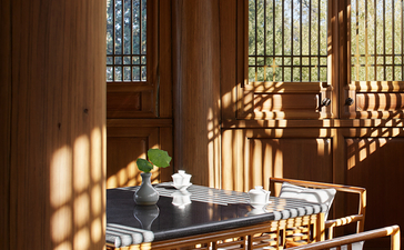 Sunlit dining area at Amandayan with wooden screens casting geometric shadows across a table set for two.