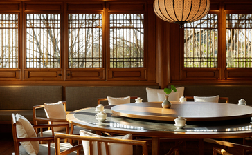 Circular dining table with chairs in a wood-panelled room at Amandayan, with latticed windows and hanging lantern.