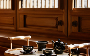 Traditional tea service set on low wooden table at Amandayan, with vertical latticed screens casting striped shadows in background.