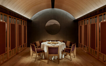 Dining room at Amanyangyun with vaulted ceiling, round table set for service, and wooden panelled walls.