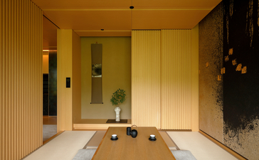 Takagamine Suite lounge area at Aman Kyoto resort, with wooden panelling, low seating, and sliding doors opening to a garden view.