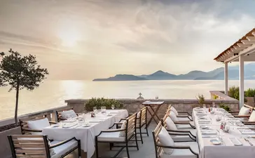 Dining Arva at Aman Sveti Stefan with Adriatic Sea views and distant mountains beyond.