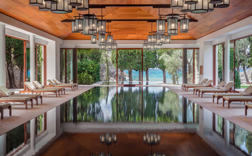 Symmetrical corridor at Aman Sveti Stefan with arched ceilings, chandeliers, and waterfront views through central archway.