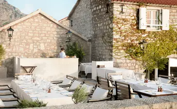 Dining terrace at Aman Sveti Stefan with stone architecture and outdoor seating.