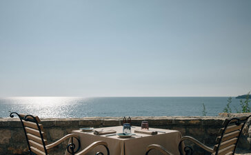 Dining piazza at Aman Sveti Stefan with views across the Adriatic Sea towards distant mountains.