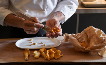 Chef plating dish at Aman Venice, hands arranging food on white plate with golden elements.