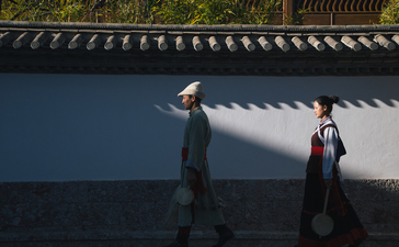 Two people stand before a traditional Asian building with blue walls and ornate roof details at Amandayan.