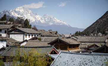 Amandayan nestled in a mountain valley with traditional architecture and snow-capped peaks beyond.