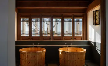 Wooden bathtubs in a spa treatment room at Amandayan, with latticed windows overlooking the garden.