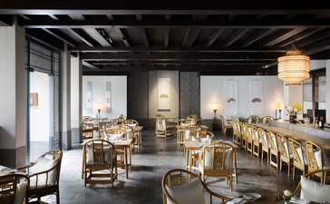 Amanfayun dining venue with wooden tables, chairs, and warm lighting beneath exposed ceiling beams.
