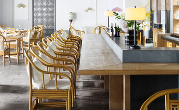 Dining area at Amanfayun with wooden chairs and table overlooking the kitchen.