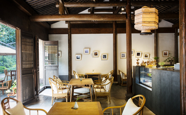 Dining room at Amanfayun with wooden beams, large windows, and contemporary furnishings in warm tones.