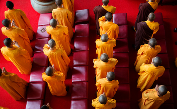 Buddhist monks in saffron robes seated in rows at Amanfayun.